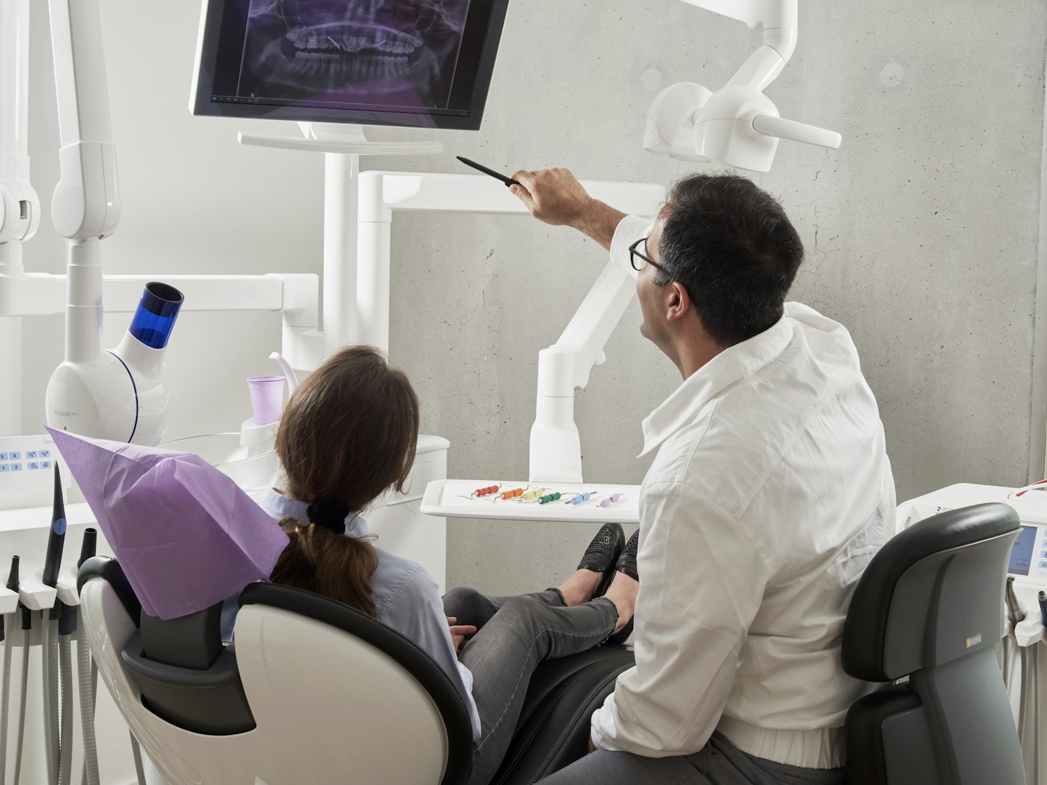 Un dentiste examine un scanner avec un patient installé dans le fauteuil