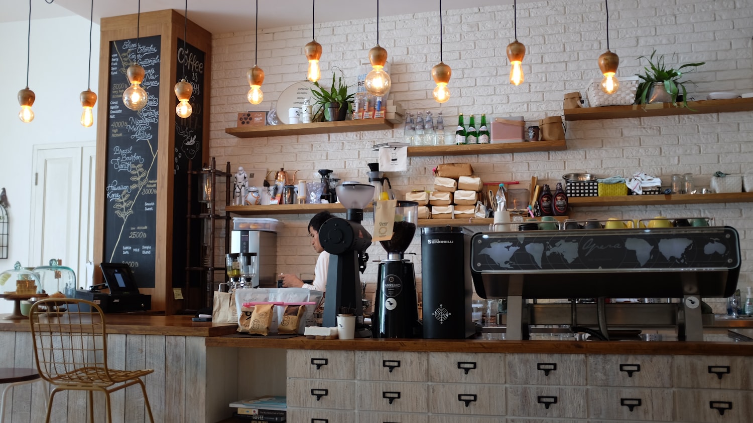 A barista working the espresso bar in a busy café