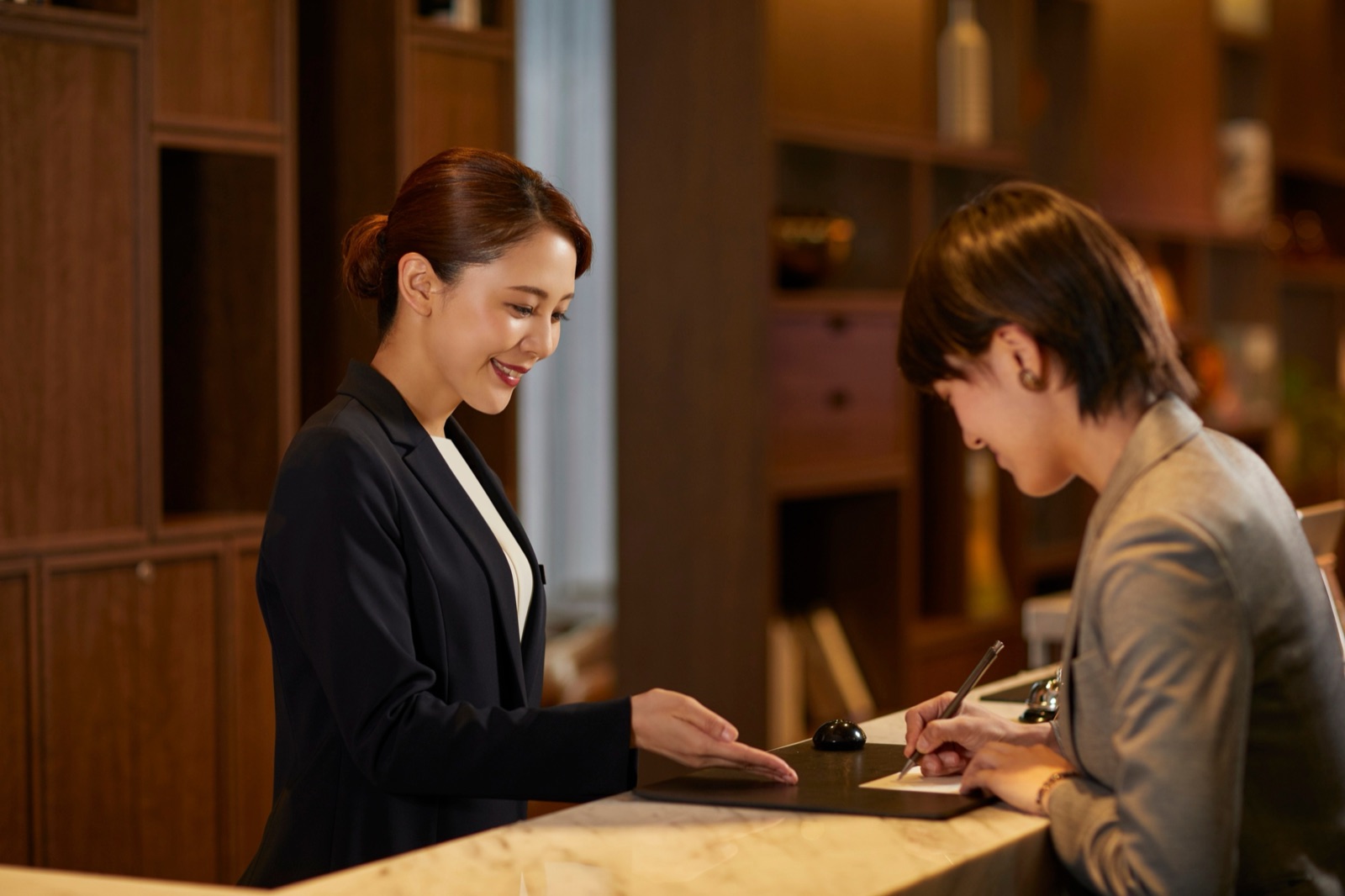 A hotel receptionist helping a guest check in at the front desk